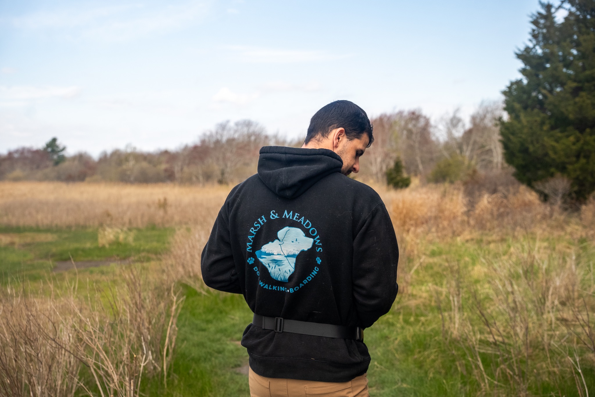 Jake wearing the Marsh and Meadows logo on a coastal trail